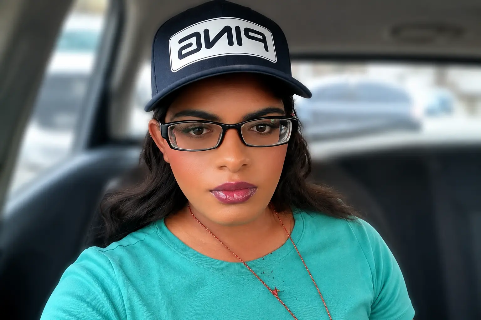 Photo of me in a navy cap and glasses, sitting in a car